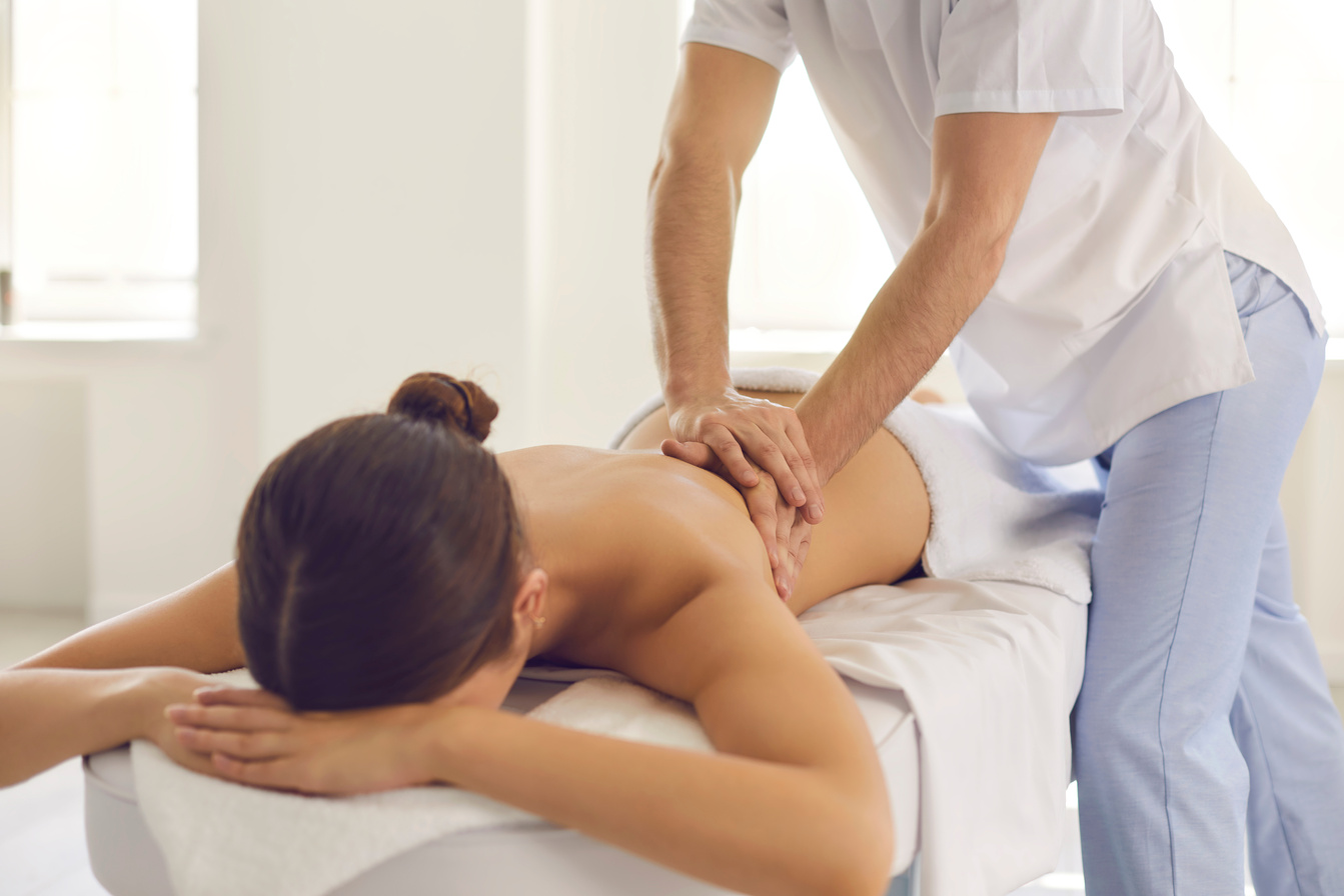 Woman Lying on Massage Table Getting Medical Back Massage in Modern Physiotherapy Center